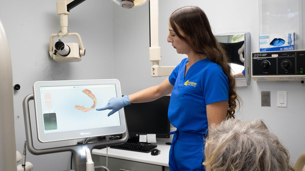 Dental assistant explains x-ray findings to patient